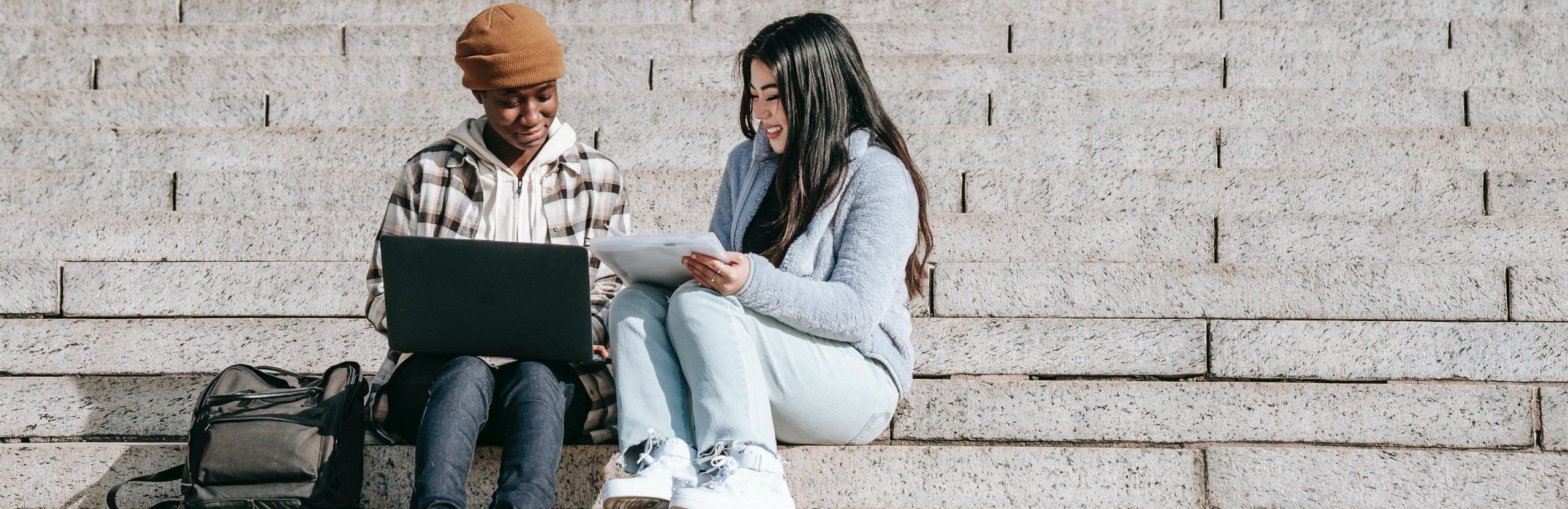 SEEK Program-Two students sitting on steps working together with a laptop. Two students sitting on steps working together with a laptop.